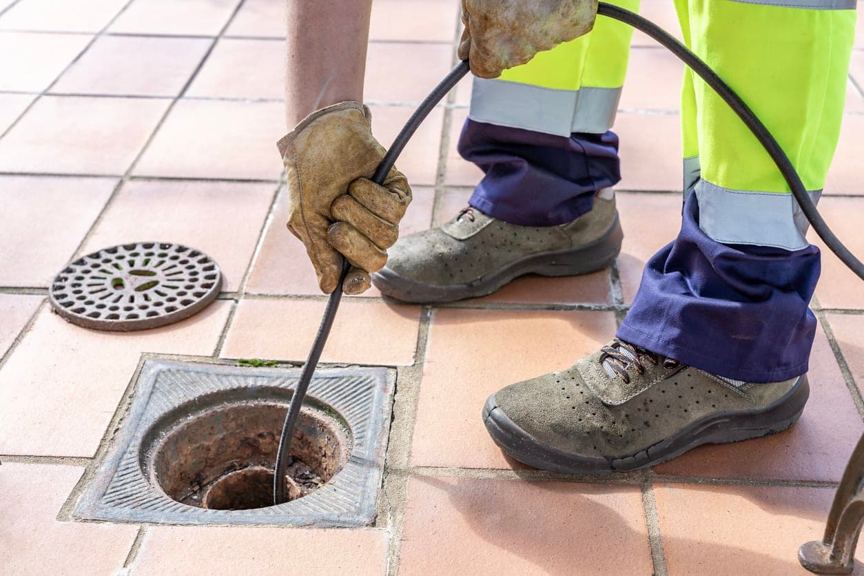 Drianage Engineer using high pressure water jetting in small open drain during hot weather